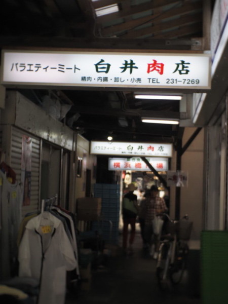横浜橋商店街の中にある横浜橋市場内、白井肉店の看板が暗闇に光る画像