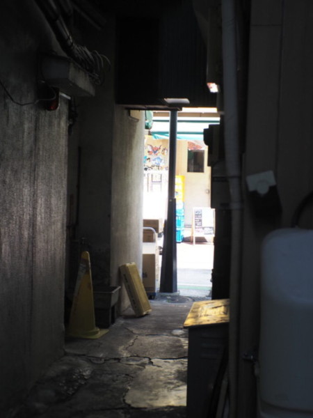 六角橋仲見世通から横道にある暗い通路、向こう側に明るい通りが見える画像