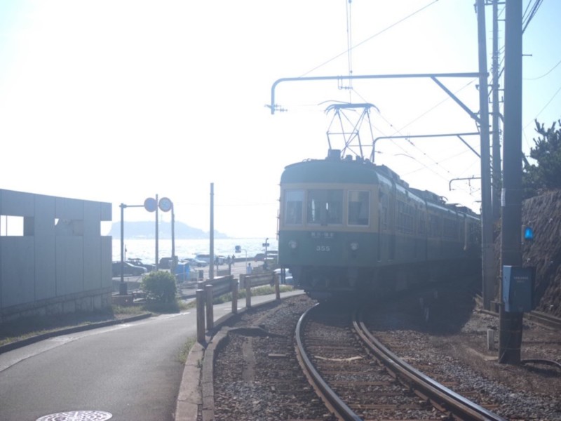 江ノ島をバックに江ノ電の355形が走る風景