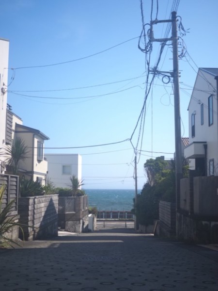 稲村ヶ崎の路地の向こう側に国道134号線と海が見える画像