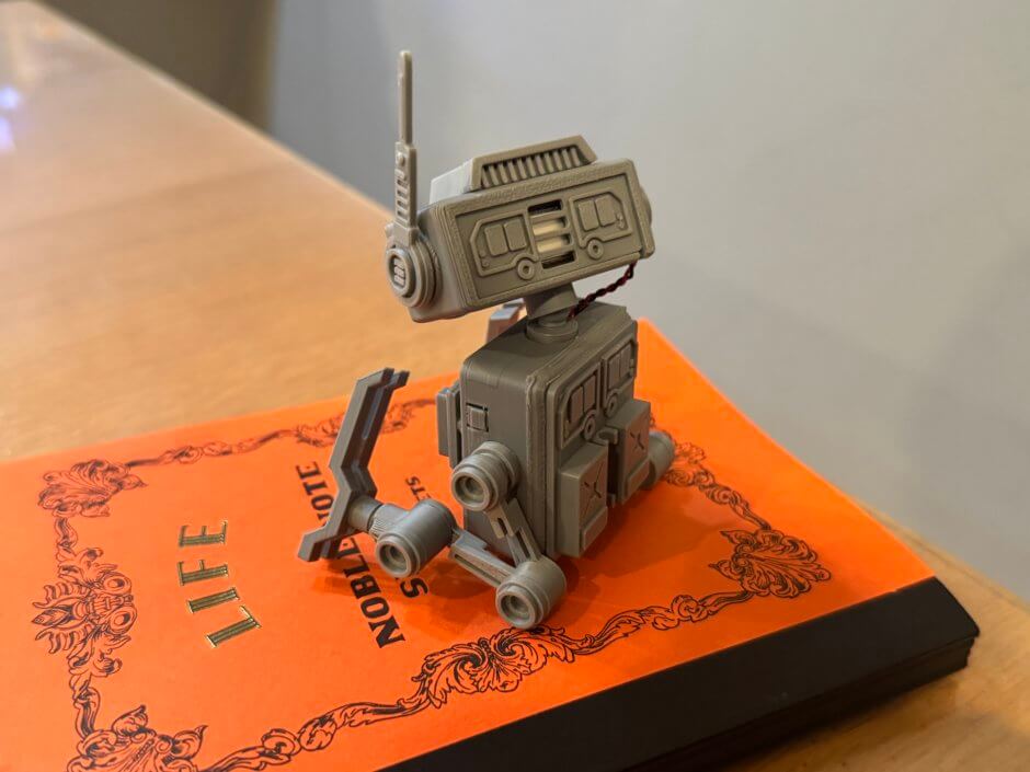 レトロなノートの上にちょこんと鎮座しているドロイドの写真後ろから