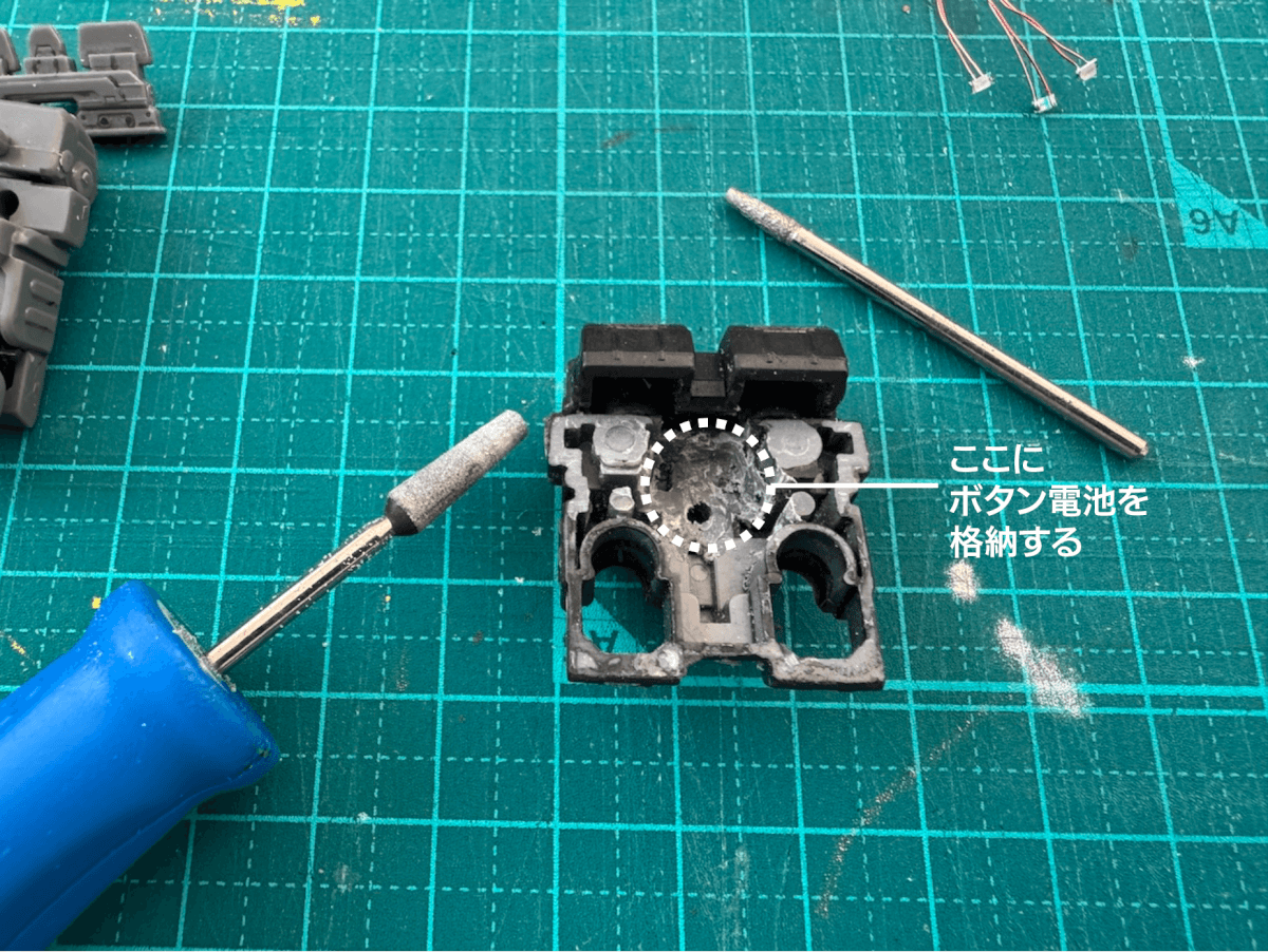 小型宇宙船のプラモデル内を削ってボタン電池を入れようとしている画像